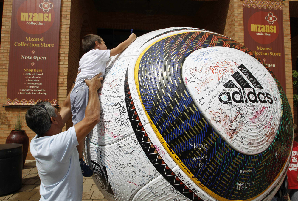 طفل يضع توقيعه على كرة قدم عملاقة في ساحة نلسون مانديلا في ساندتون قبل 64 يوما من انطلاق نهائيات كأس العالم لكرة القدم.
