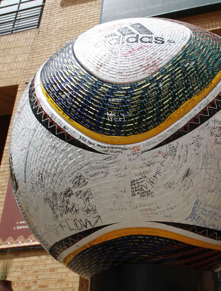 طفل يضع توقيعه على كرة قدم عملاقة في ساحة نلسون مانديلا في ساندتون قبل 64 يوما من انطلاق نهائيات كأس العالم لكرة القدم.