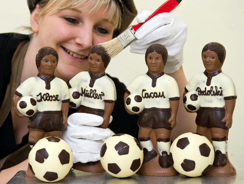 عاملة في مصنع للشوكولاته في ألمانيا تقف أمام مجسمات مصنوعة من الكاكاو لأربعة من لاعبي المنتخب الألماني المشارك في كأس العالم