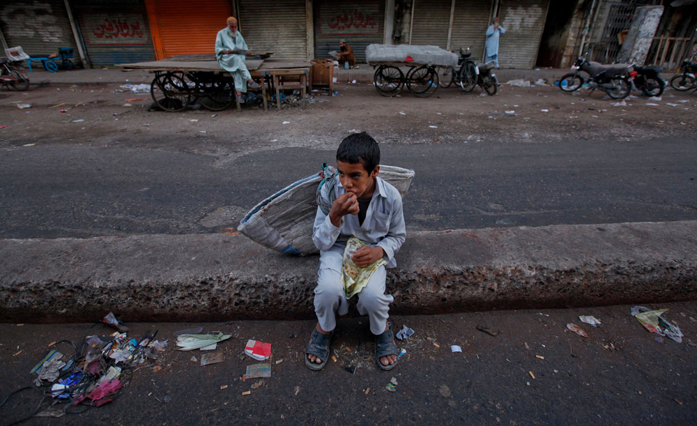 طفل يأكل فطوره الصباحي على قارعة الطريق في كراتشي