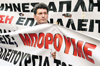 عامل في مصنع معادن يحمل لافتة خلال تظاهرة تطالب بدفع الرواتب المتأخرة في العاصمة اليونانية أثينا