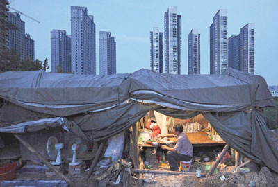 عامل يحضر طعام العشاء تحت سقيفة في موقع بناء مجمع سكني في مقاطعة أنهوى الصينية