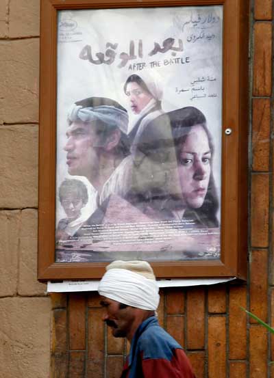 رجل يسير أمام ملصق لفيلم "بعد معركة" في أحد شوارع القاهرة