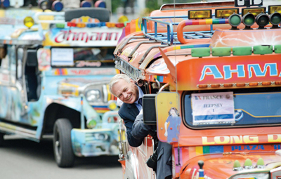 جان مارك أيرول رئيس وزراء فرنسا يطل من نافذة سيارة جيب في مدينة سيبو الفلبينية