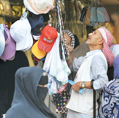 متسوق ينظر إلى حقائب وقبعات في محل تجاري قرب المسجد الحرام في مكة المكرمة