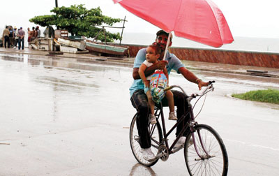 ناس وناس :رجل ينقل طفلته معه على دراجته بعد أن أطلقت الحكومة الجامايكية تحذيرات بشأن إعصار ساندي الذي بدأ يقترب من السواحل الجام