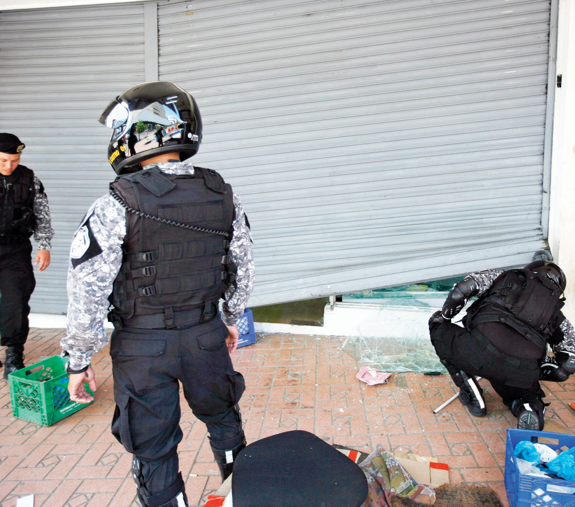 رجال الشرطة يفتشون أحد المتاجر التي نهبت خلال الاحتجاجات ضد قانون الحكومة الجديدة الذي يسمح ببيع الأراضي في منطقة التجارة الحرة 