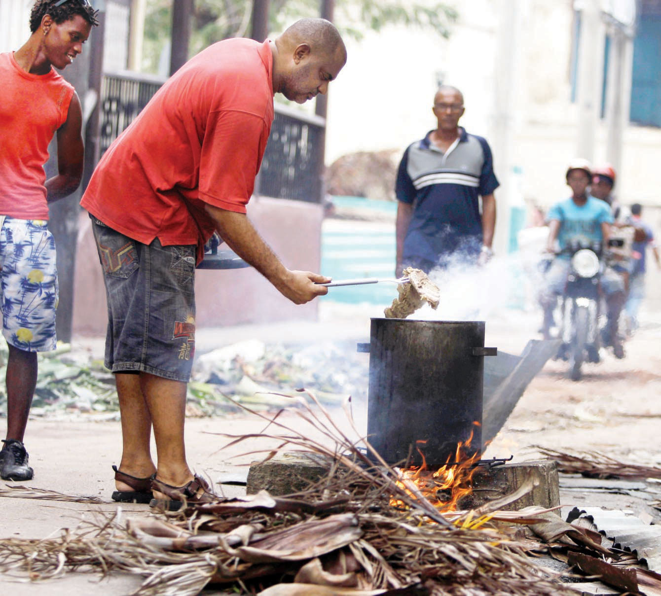 رجل يحرق الأخشاب لطهي الطعام مع جيرانه في شارع وسط سانتياجو الكوبية