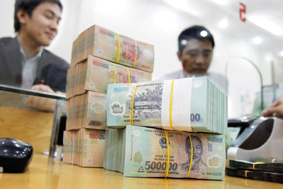 رجلان يقفان خلف أوراق نقدية بعملة فيتنام «دونج» في مدينة هاي فونج