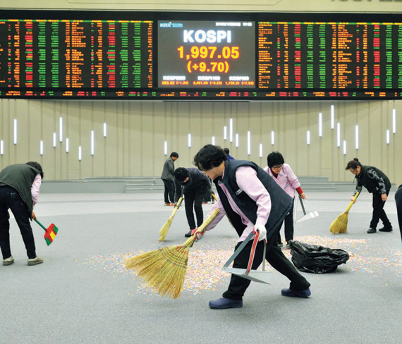عمال ينظفون بورصة سيئول أمس بمناسبة اختتام عام 2012 وسط تباطؤ اقتصادي عالمي