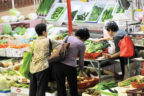 نساء يتسوقن الخضراوات في سوق تجارية في سنغافورة