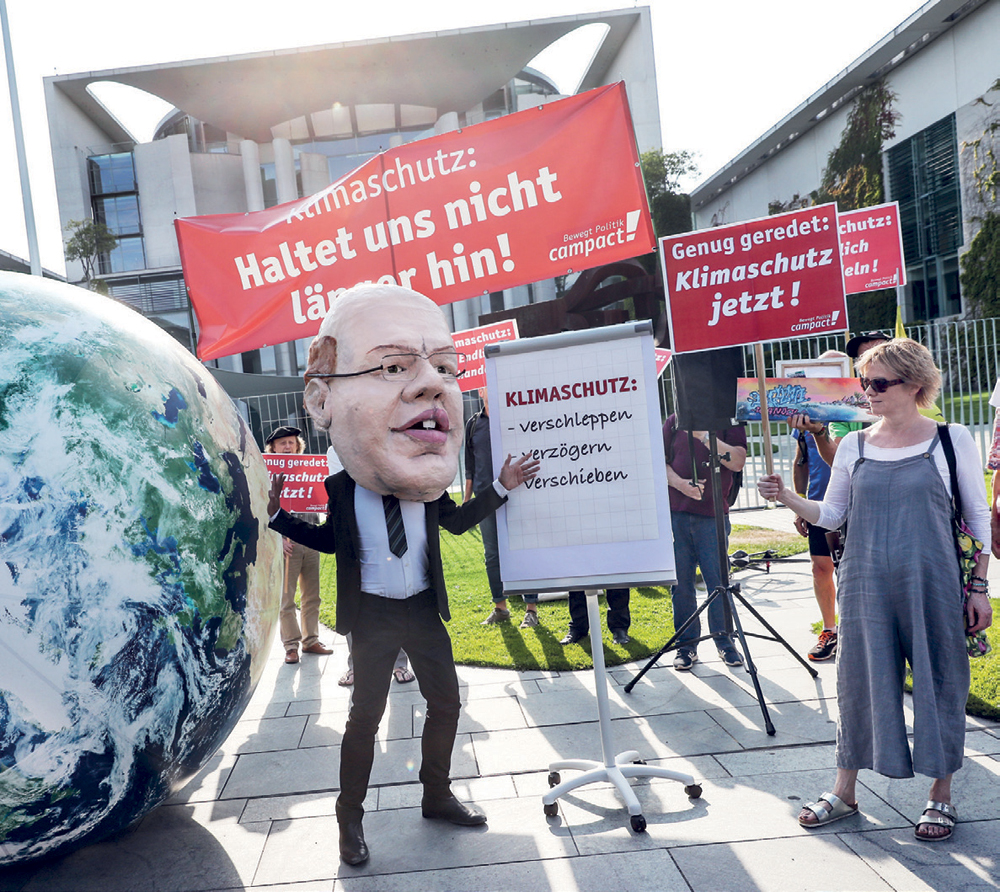 متظاهرون يحملون قناعا لوزير الاقتصاد الألماني مطالبين بحماية المناخ وفرض ضرائب على المصانع لخفض انبعاثات الكربون في ألمانيا