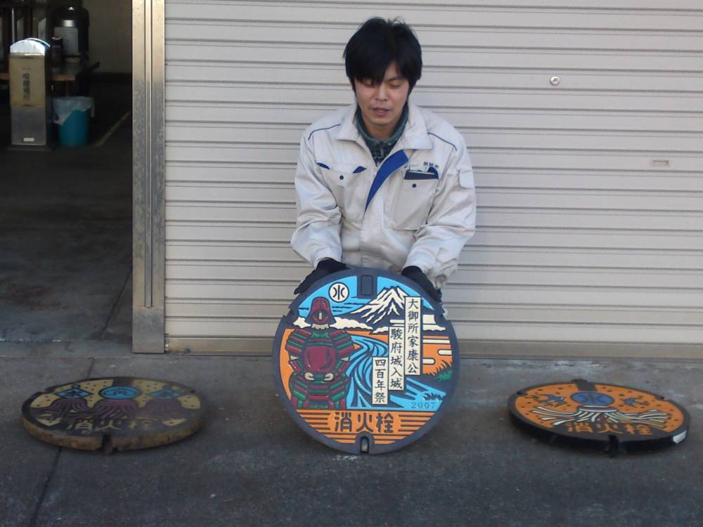 عامل ياباني يعرض نماذج من أغطية المجاري في طوكيو.