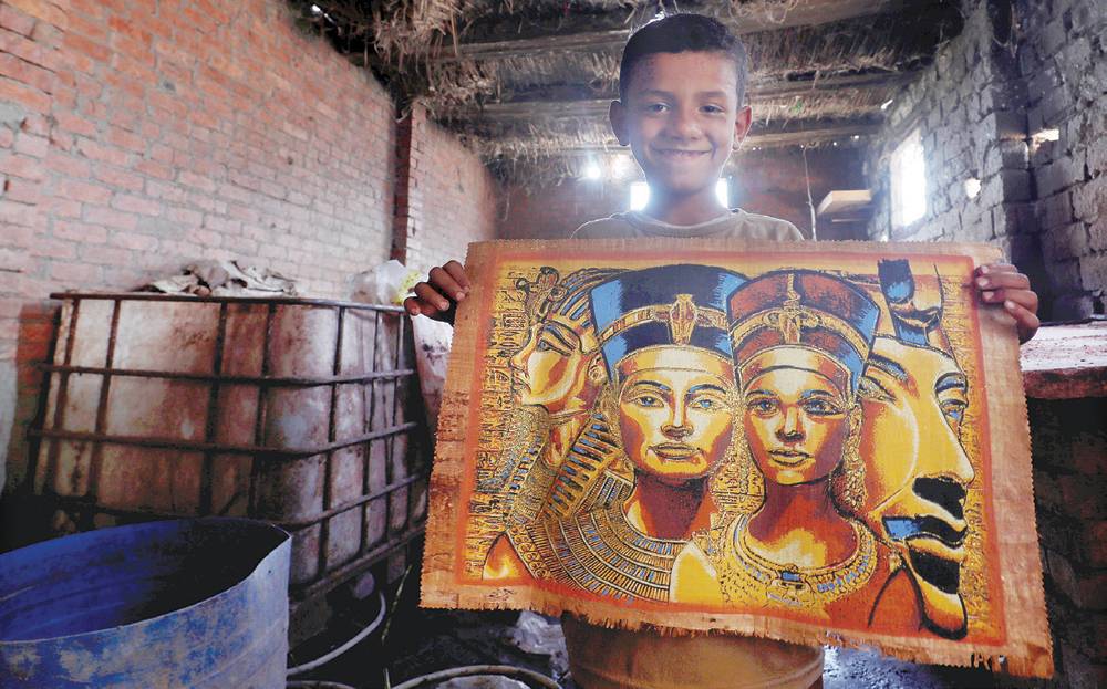 طفل يحمل ورقة بردي رسم عليها بعض ملوك الفراعنة.   "رويترز"