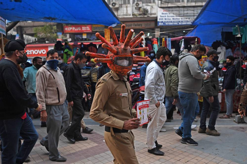 رجل أمن يرتدي خوذة مستوحى من شكل فيروس كورونا وذلك خلال حملة توعية عن الفيروس في نيودلهي الهندية. "الفرنسية"