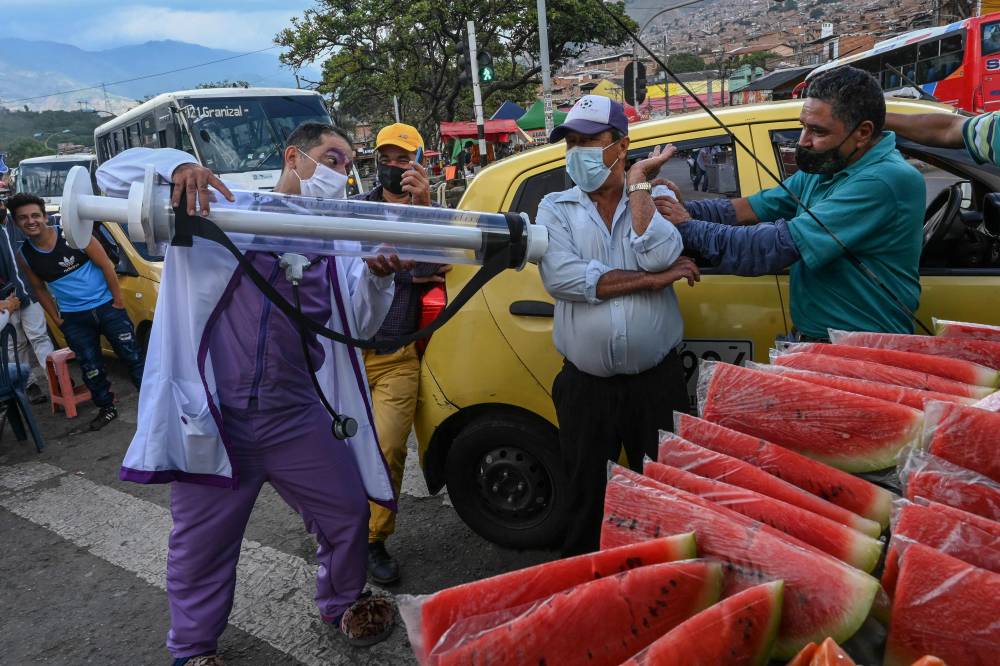 فنان كولومبي يتفاعل مع المواطنين خلال حملة للترويح للتطعيم ضط كورونا في شوارع ميديلين ثاني أكبر مدن البلاد."الفرنسية"