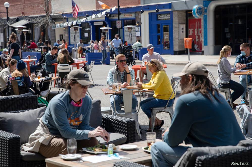 أشخاص يتناولون الغداء في مطعم يقدم خدماته في الهواء الطلق في مدينة آن آربور في ولاية ميشيغان التي خففت القيود الخاصة بكوفيد 19. "رويترز"