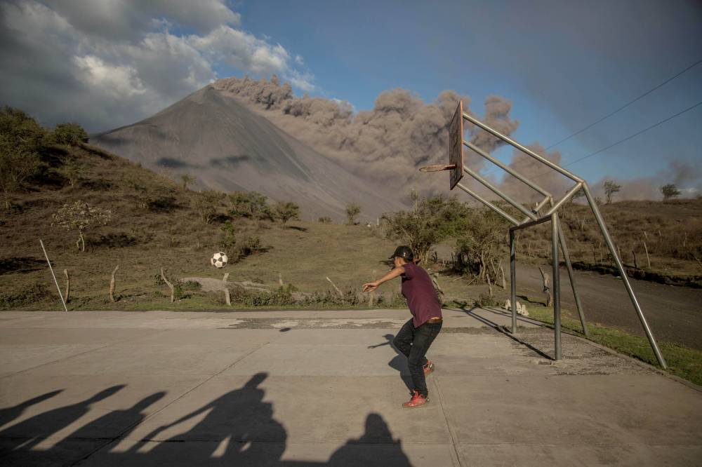 رجل يلعب كرة القدم بينما يثور بركان باكايا الواقع في قرية إل روديو في جواتيمالا. "إ. ب. أ"