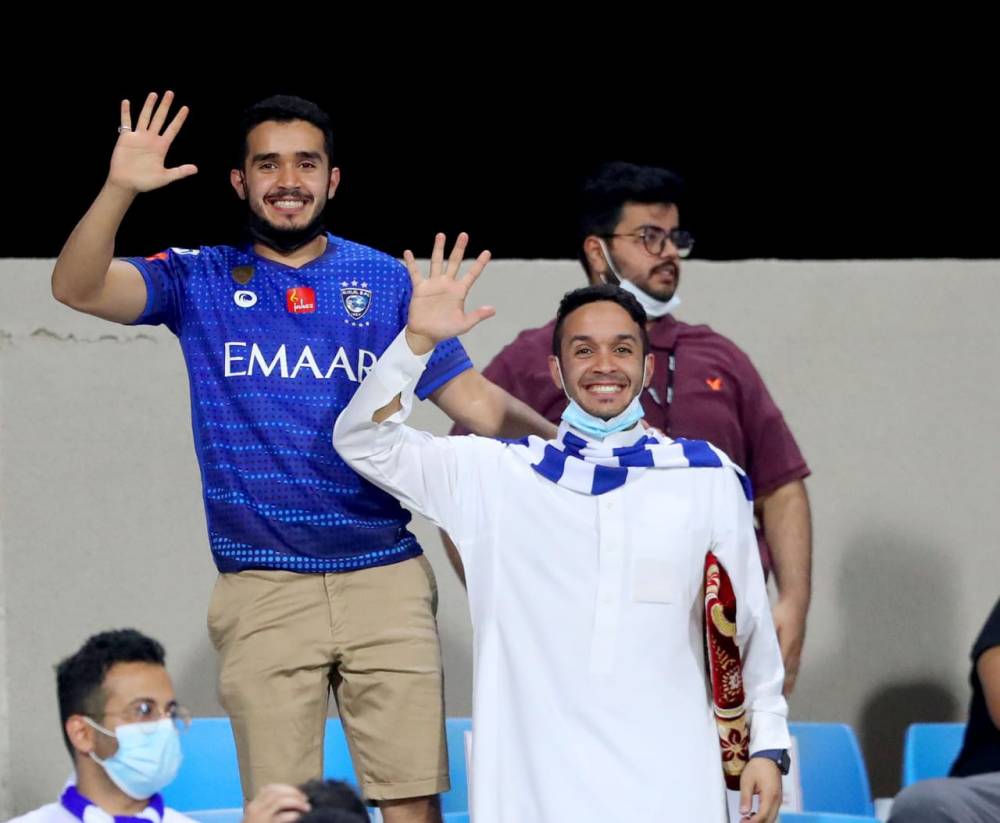 مشجعين هلاليين يرفعون ايديهم بالخمسة.