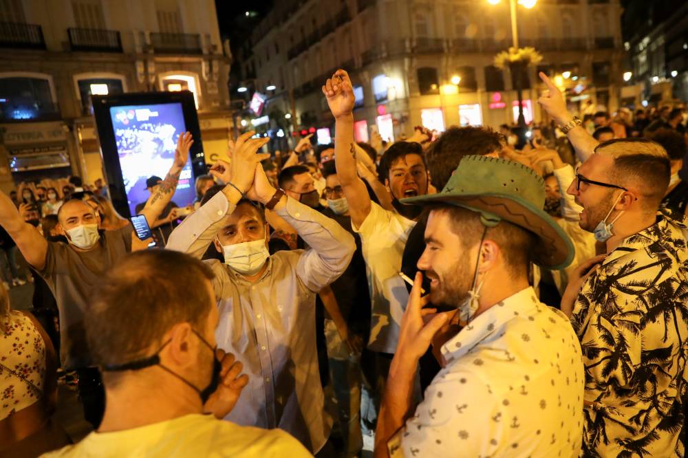 مواطنون أسبان يحتفلون بتخفيف التدابير الصحية في ساحة بويرتا ديل سول في مدريد أمس."رويترز"