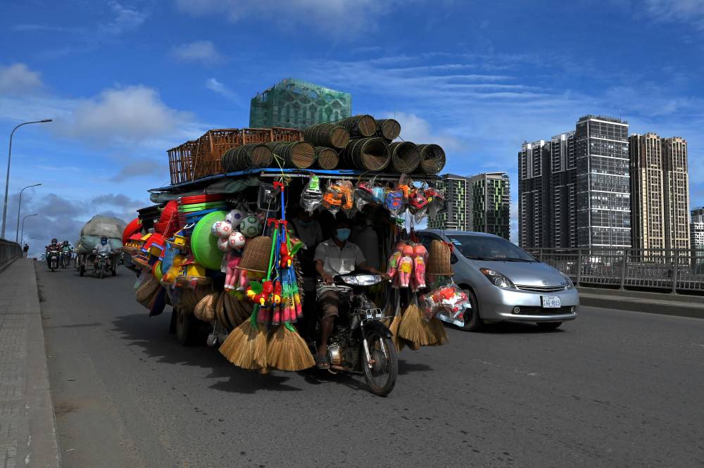 رجل يقود عربة محملة بالبضائع، تبدو كمتجر متنقل، في بنوم بنه، كمبوديا."الفرنسية"