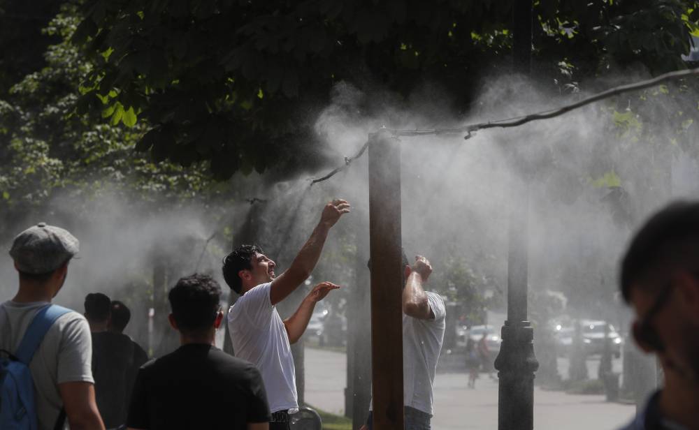 أوكرانيون يتجمعون حول رشاش مائي معلق لتبريد أنفسهم، وذلك بعد ارتفاع درجات الحرارة في كييف. "إ. ب. أ"