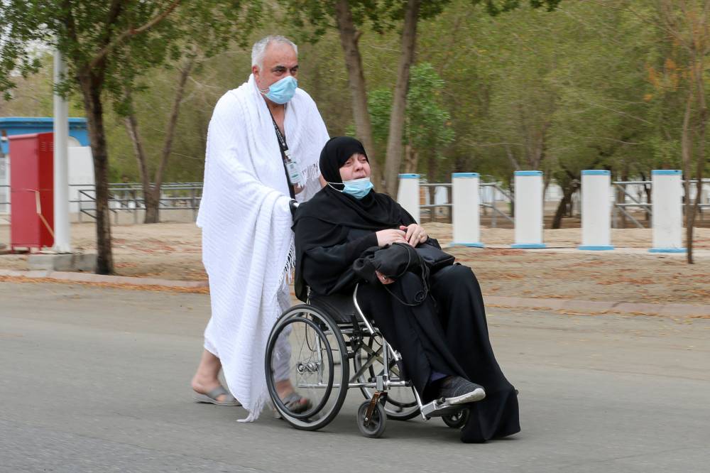 حاج يدفع مسنة على كرسي متحرك على صعيد عرفة."رويترز"
