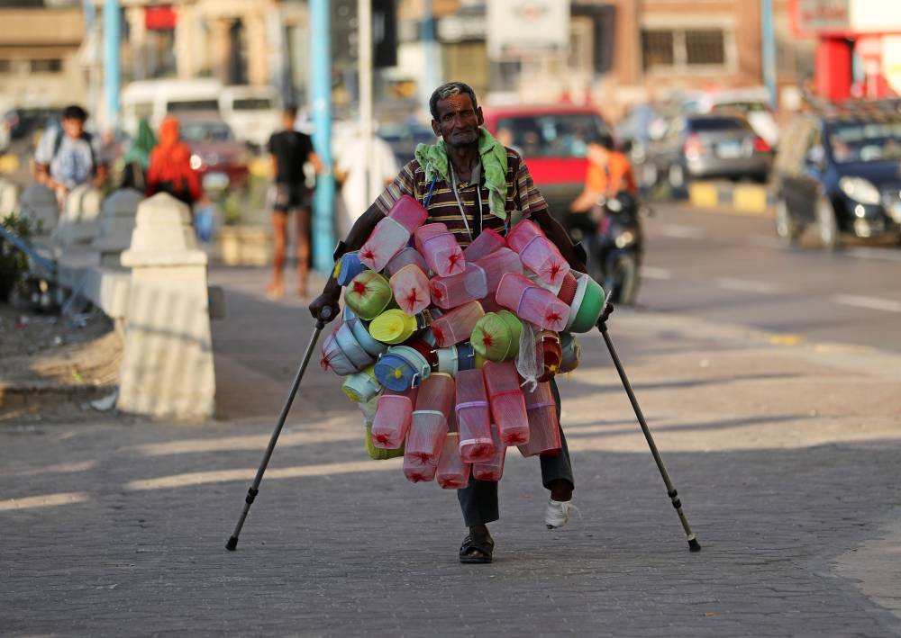 بائع مصري يمر أمام شاطىء لذوي الإعاقة في الإسكندرية."رويترز"