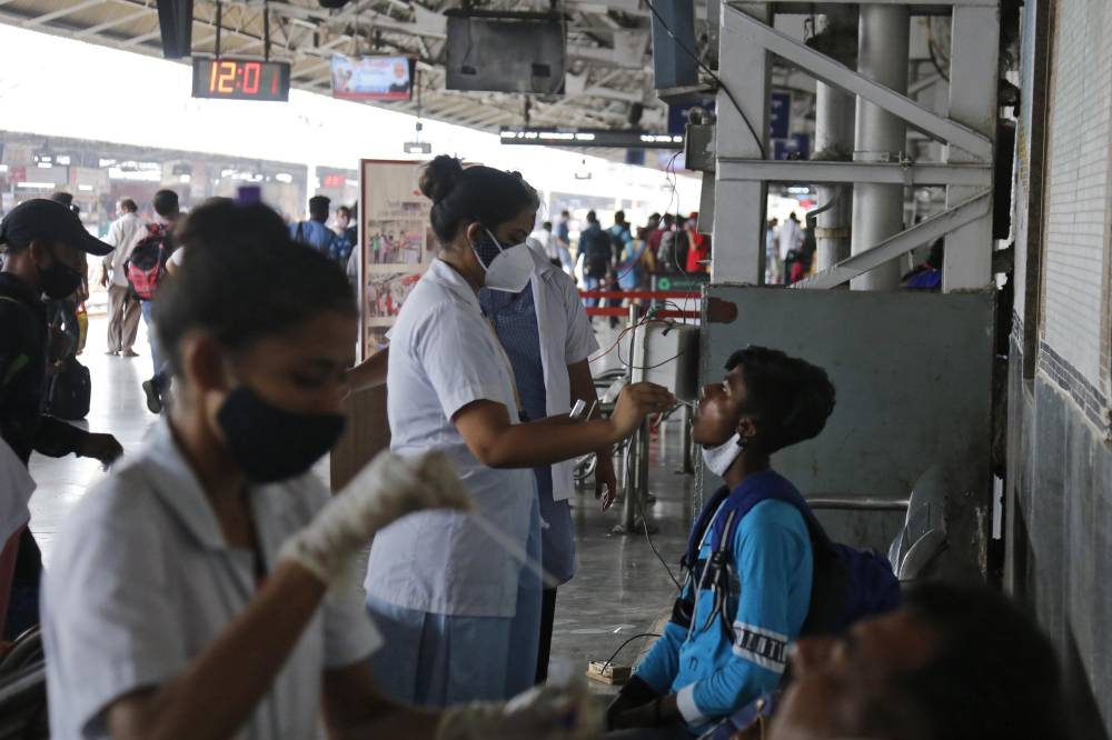 عاملون صحيون يأخذون مسحة طبية من مواطنين في محطة سكك حديد في أحمد أباد."أ. ب"