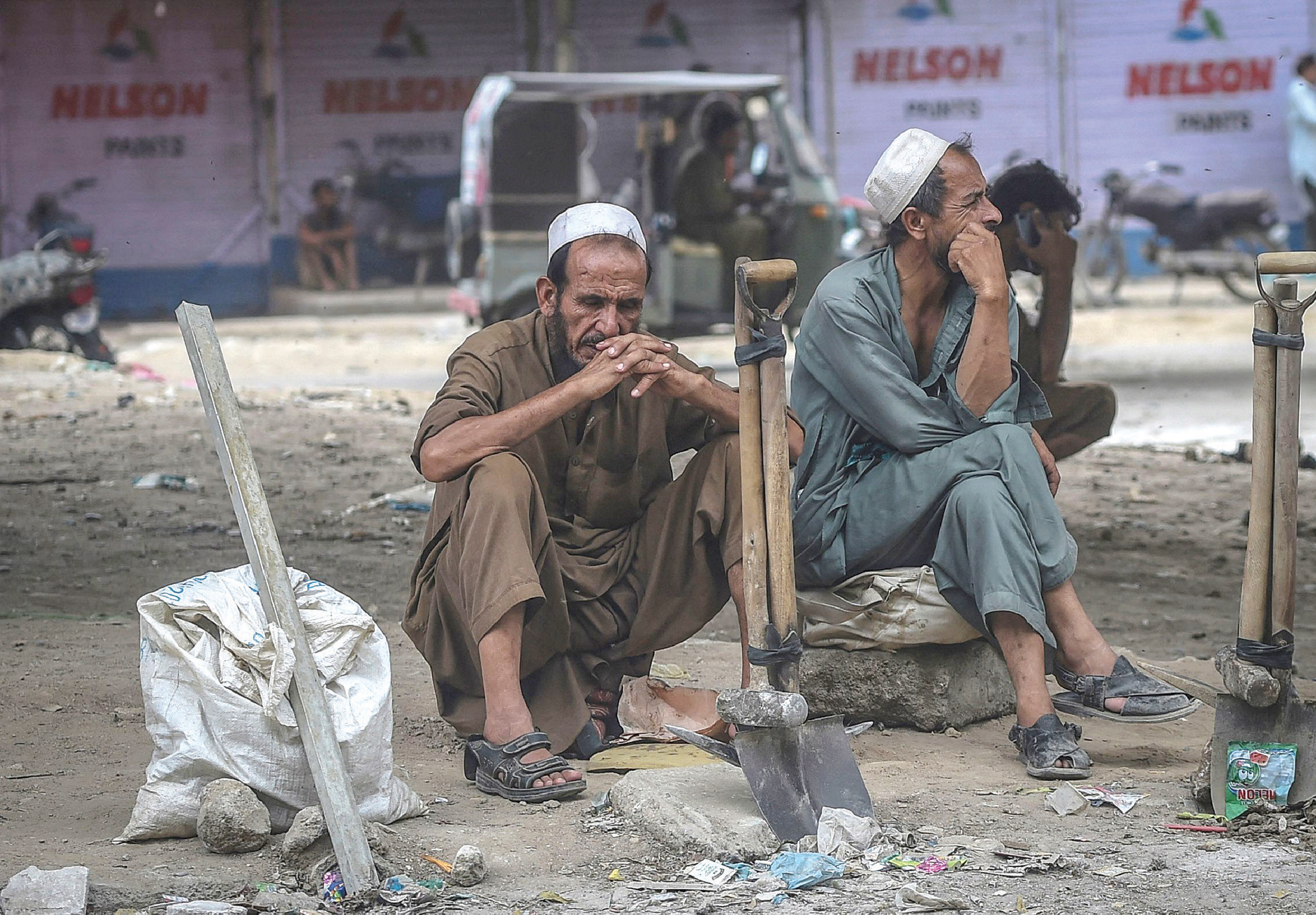 عاملان بأجر يومي خلال انتظارهما الزبائن في أحد شوارع كراتشي