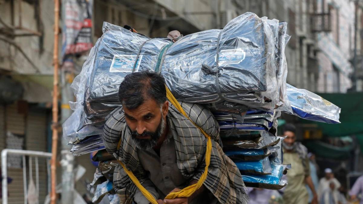 عامل ينقل كمية من الأقمشة في سوق كراتشي.