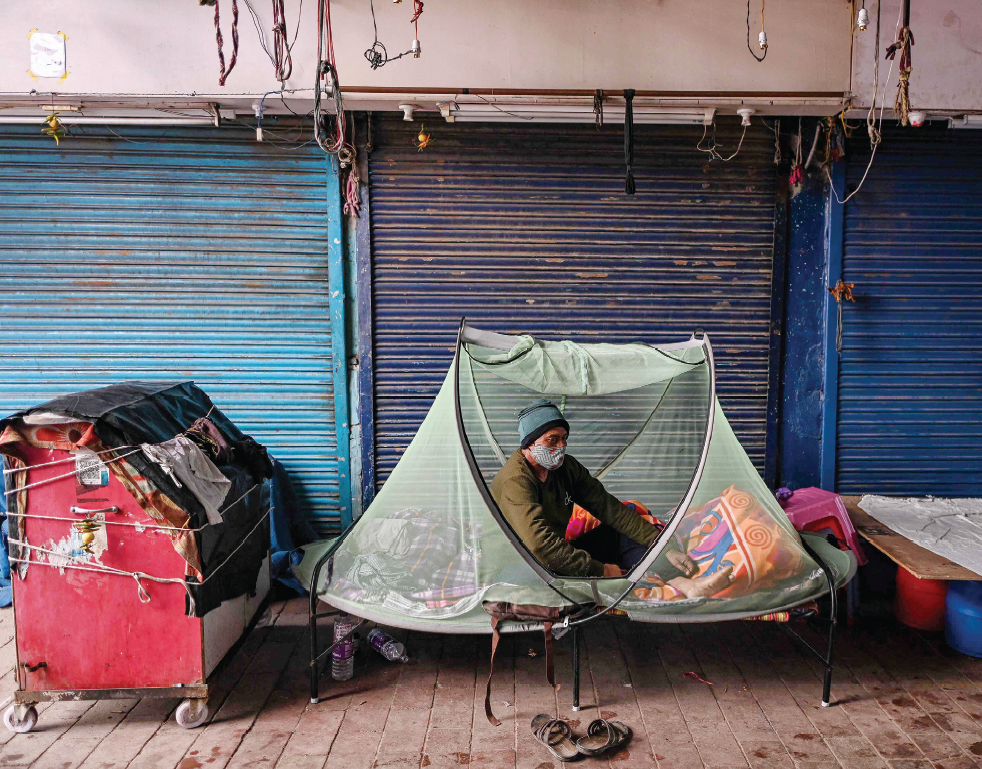 عامل يهيئ مكانا لنومه بجوار محال مغلقة بعد منع التجول الذي فرضته الحكومة الهندية