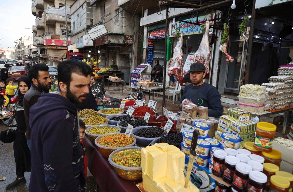 سوريون يشترون المواد الغذائية قبل حلول رمضان في أحد شوارع إدلب.