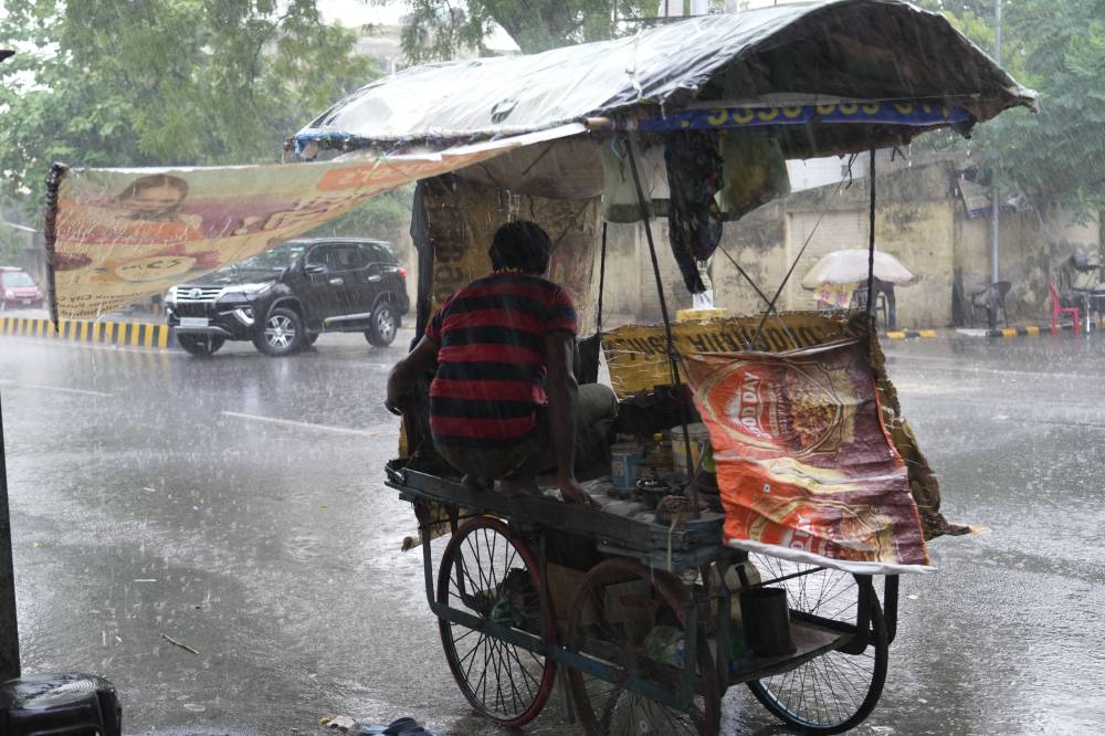 بائع هندي يحتمي داخل عربته أثناء هطول أمطار غزيرة في ولاية أتر براديش. «الفرنسية »