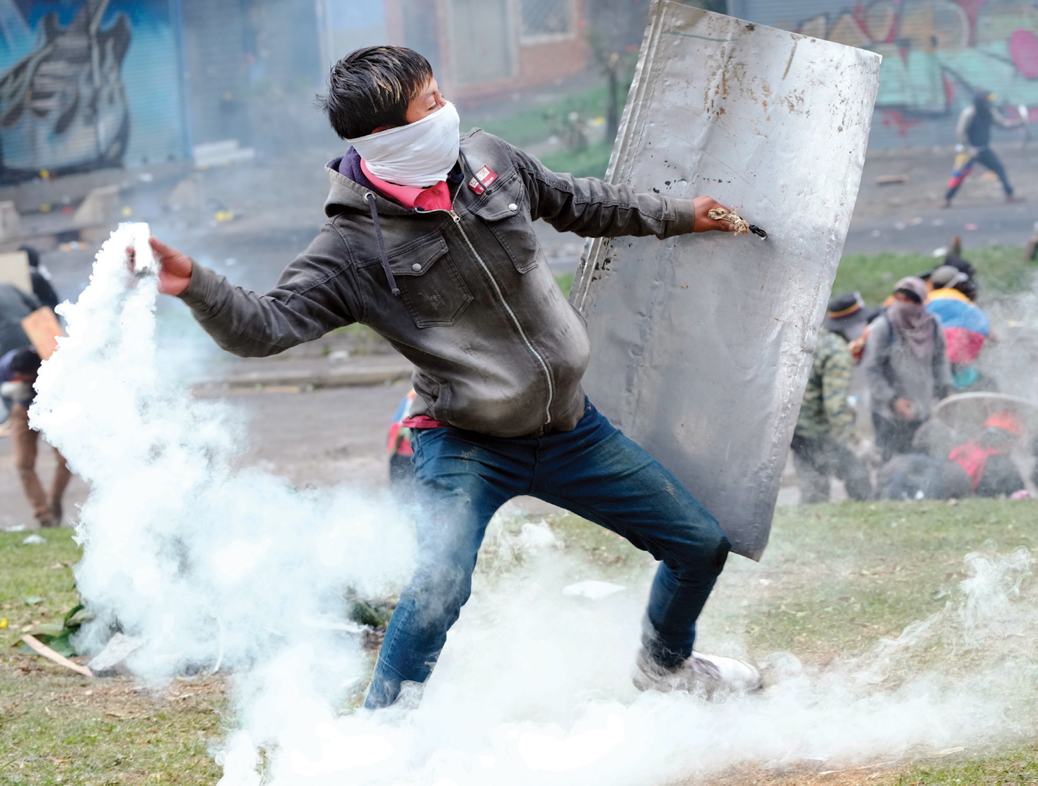 متظاهر يعيد عبوة غاز مسيل للدموع خلال اشتباكات مع الشرطة في الإكوادور