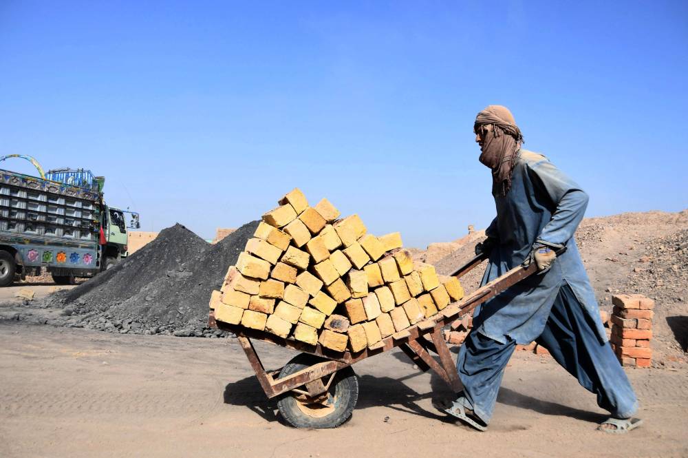 أفغاني يدفع عربة يدوية في أحد أفران الطوب، التي تعد من الأعمال الخطرة الأكثر شيوعا في البلاد. «الفرنسية»