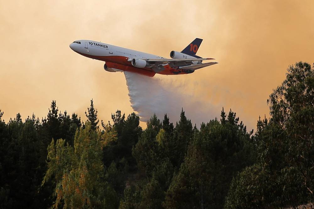 طائرة تلقي الماء على حرائق الغابات المندلعة لأكثر من أسبوع في منطقة لوس ريوس التشيلية. «الفرنسية»
