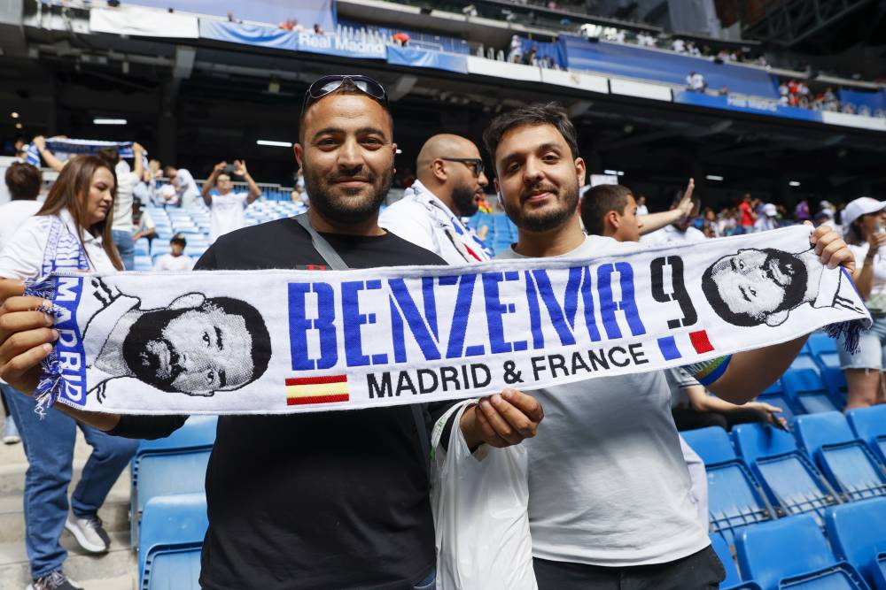 مشجعو الريال يحملون وشاحا يصور المهاجم بنزيما. إ.ب.أ