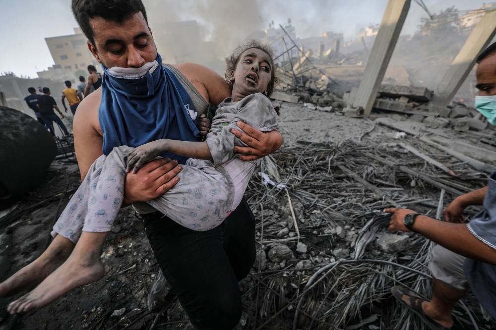 فلسطيني ينتشل طفلة من تحت الأنقاض. "إ. ب"