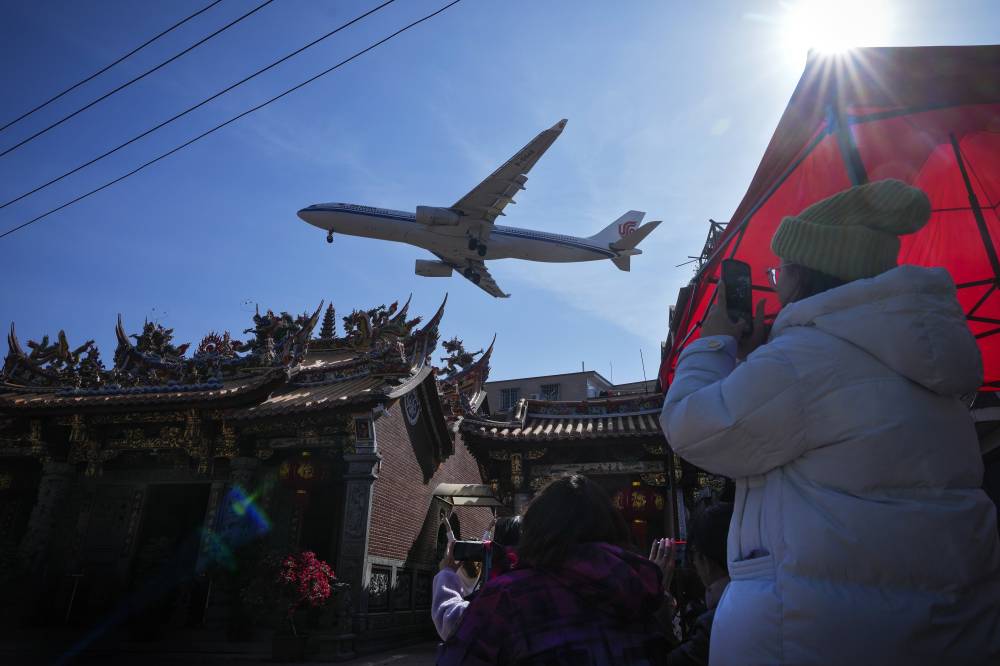 صينيون يلتقطون صورا لطائرة تحلق فوق أحد أحياء محافظة فوجيان. "أ.ب"
