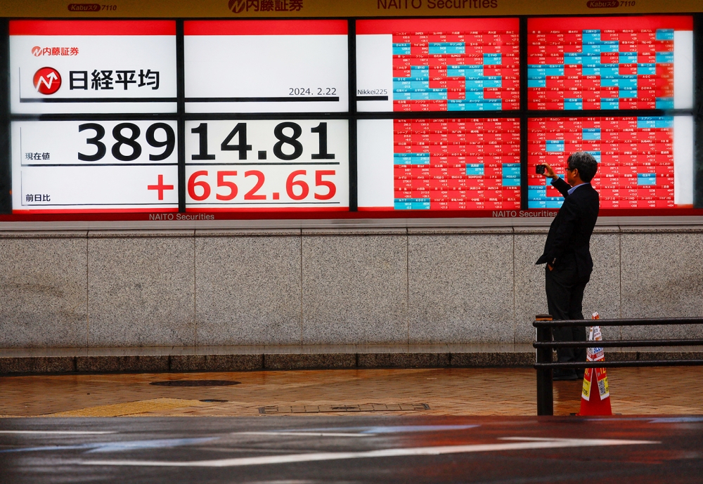 رجل يلتقط صورة لشاشات إلكترونية تعرض متوسط ​​أسهم نيكي الياباني خارج شركة وساطة في طوكيو. رويترز