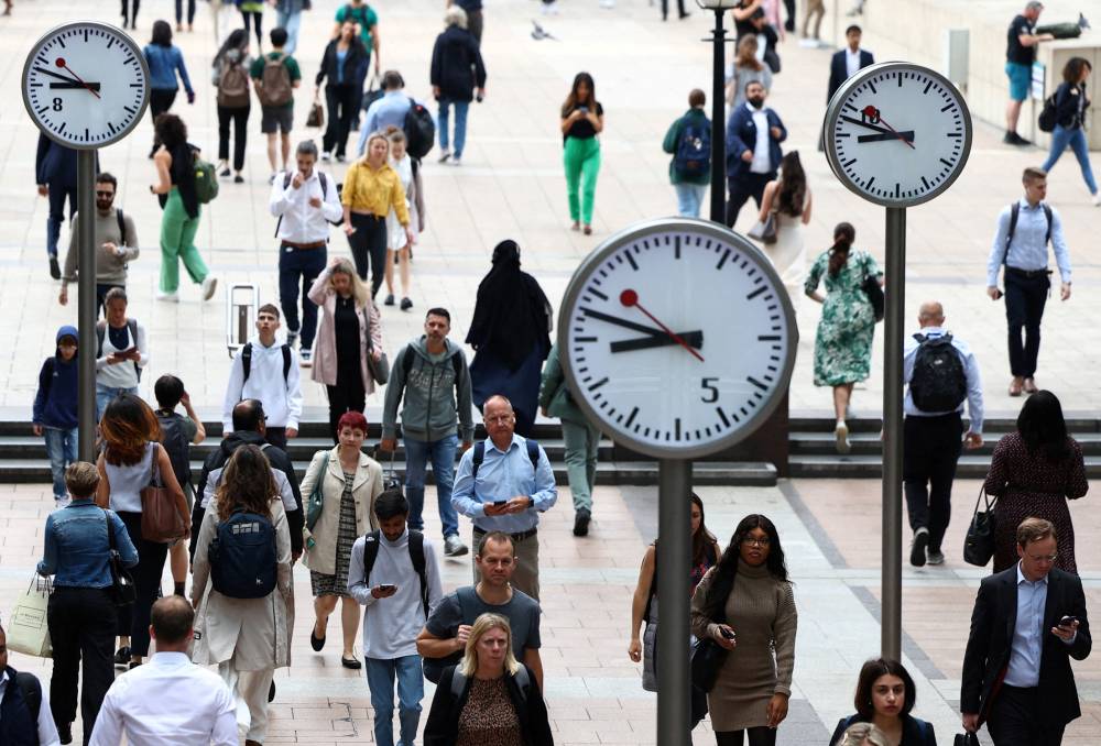 FILE PHOTO: Workers walk through the Canary Wharf financial district, ahead of a Bank of England decision on interest rate changes, in London, Britain, August 3, 2023. REUTERS/Toby Melville/File Photo