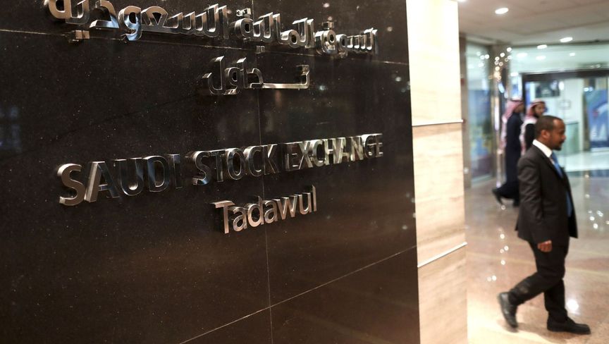 رجل يسير بجوار المدخل الرئيسي للسوق المالية السعودية