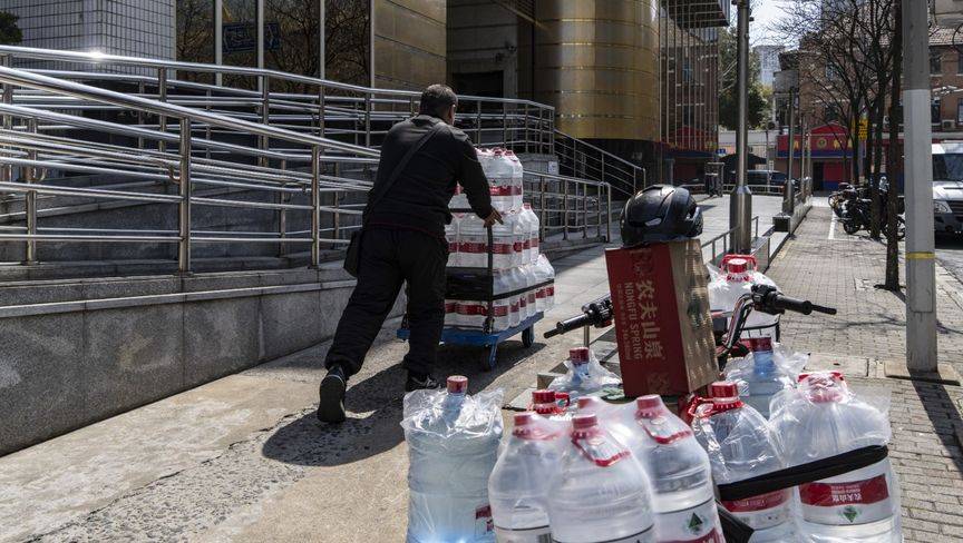 عامل يدفع عربة مملوءة بزجاجات مياه شركة "نونغفو سبرينغ" في شنغهاي. "بلومبرغ"