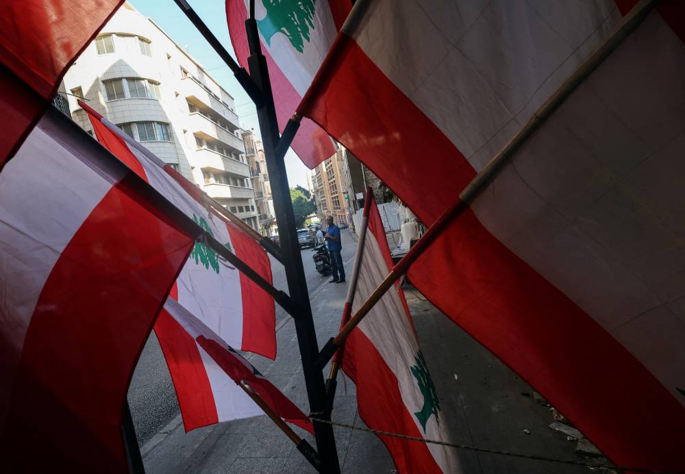 A man stands near Lebanese flags displayed for sale in Beirut, Lebanon September 24, 2024.  REUTERS/Amr Abdallah Dalsh