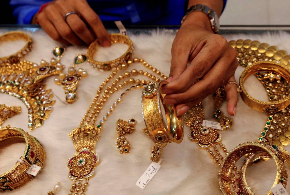 FILE PHOTO: A woman looks at a gold bangle inside a jewellery showroom at a market in Mumbai January 15, 2015. REUTERS/Shailesh Andrade/File Photo