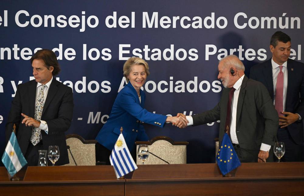 TOPSHOT - European Commission President Ursula von der Leyen shakes hands with Brazil's President Luiz Inacio Lula da Silva next to Uruguay's President Luis Lacalle Pou (L) and Paraguay's President Santiago Pena (R) during the LXV Mercosur Summit in Montevideo on December 6, 2024. Mercosur and the European Union have concluded "negotiations for a free trade agreement," European Commission President Ursula von der Leyen announced in Montevideo on December 6. (Photo by Eitan ABRAMOVICH / AFP)
