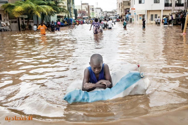 طفل يطفو على طريق غمرته المياه بعد هطول أمطار غزيرة في العاصمة السنغالية