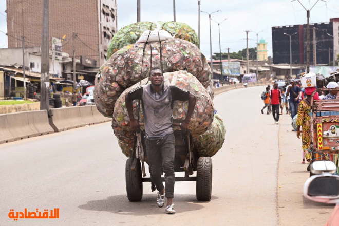 رجل يجر عربة محملة بأكياس مليئة بالعلب الفارغة في ساحل العاج