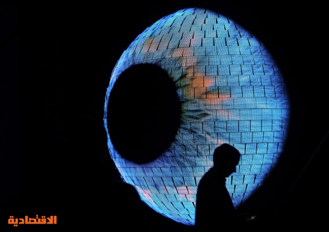 امرأتان في صورة أمام الكرة الأرضية المغطاة بآلاف المصابيح المنارة داخل "اكسبو 2010 العالمي للمعارض" الذي افتتح تحت شعار "مدينة أ